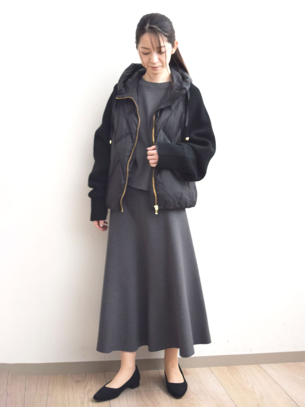 ブラック系のダウンジャケット/コート、グレー系のニット/セーター、グレー系のスカートを着用したレディースの秋コーディネートの3枚目の写真