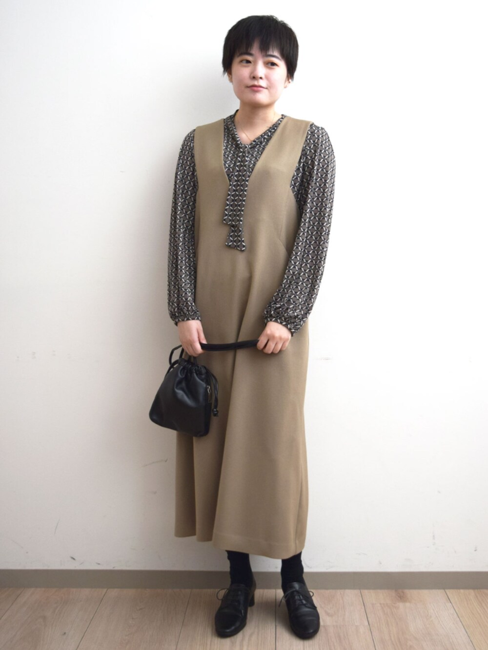 ベージュ系のジャンパースカート、ブラウン系のTシャツ/カットソーを着用したレディースの秋コーディネートの2枚目の写真