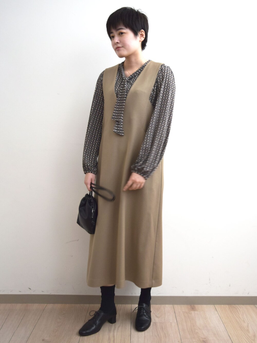 ベージュ系のジャンパースカート、ブラウン系のTシャツ/カットソーを着用したレディースの秋コーディネートの4枚目の写真