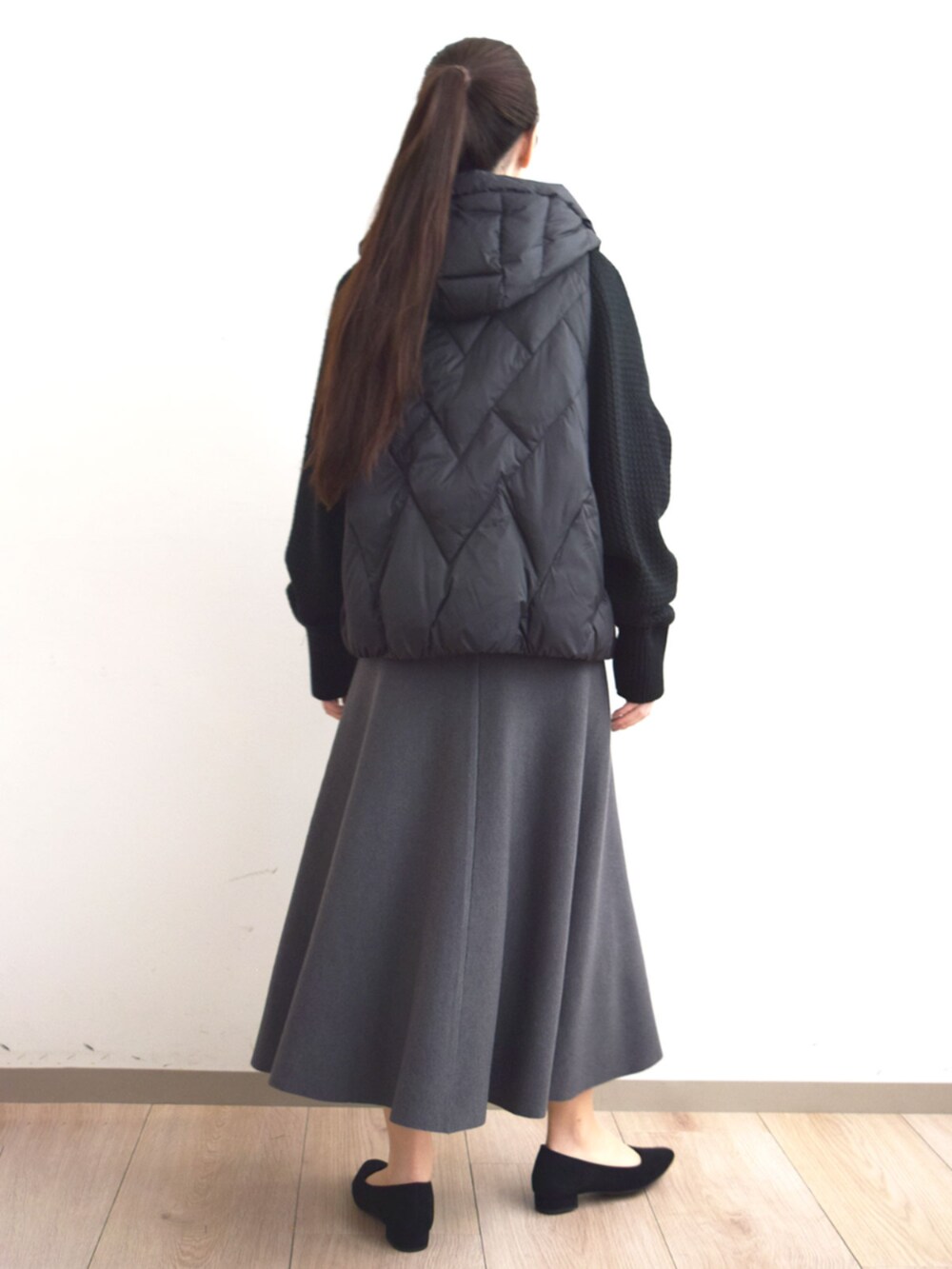ブラック系のダウンジャケット/コート、グレー系のニット/セーター、グレー系のスカートを着用したレディースの秋コーディネートの5枚目の写真
