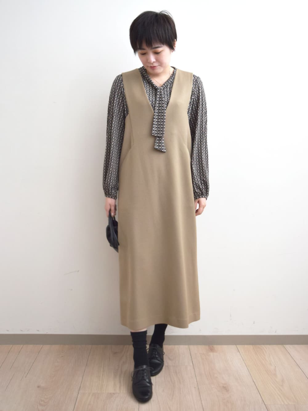 ベージュ系のジャンパースカート、ブラウン系のTシャツ/カットソーを着用したレディースの秋コーディネートの5枚目の写真