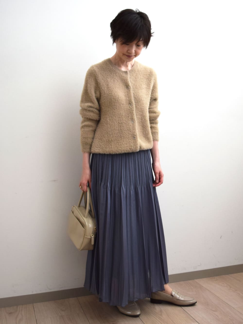 グレー系のスカート、ベージュ系のカーディガン/ボレロを着用したレディースの秋コーディネートの2枚目の写真