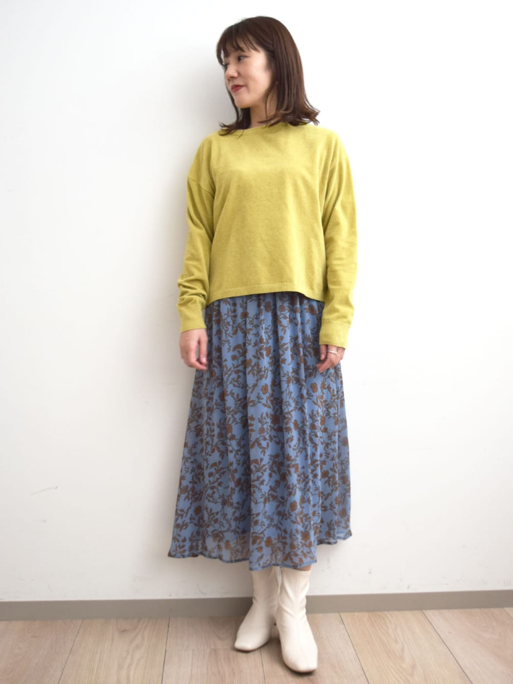 イエロー系のニット/セーター、ブルー系のスカートを着用したレディースの秋コーディネートの4枚目の写真