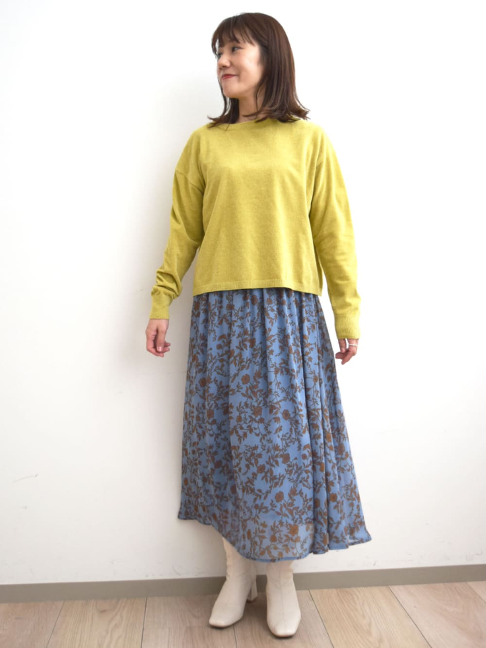 イエロー系のニット/セーター、ブルー系のスカートを着用したレディースの秋コーディネートの3枚目の写真