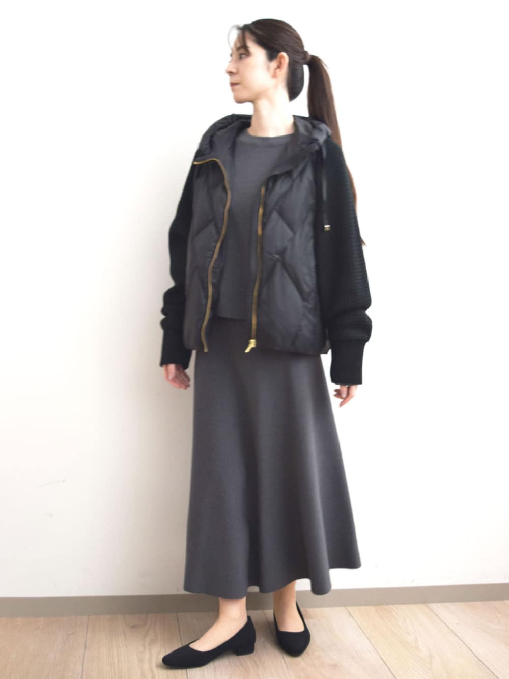 ブラック系のダウンジャケット/コート、グレー系のニット/セーター、グレー系のスカートを着用したレディースの秋コーディネートの4枚目の写真