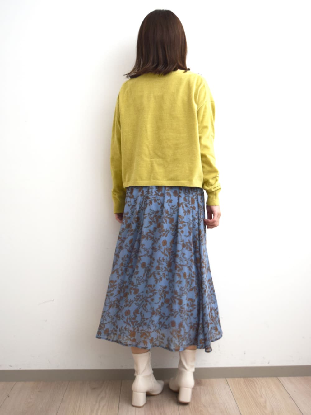 イエロー系のニット/セーター、ブルー系のスカートを着用したレディースの秋コーディネートの2枚目の写真