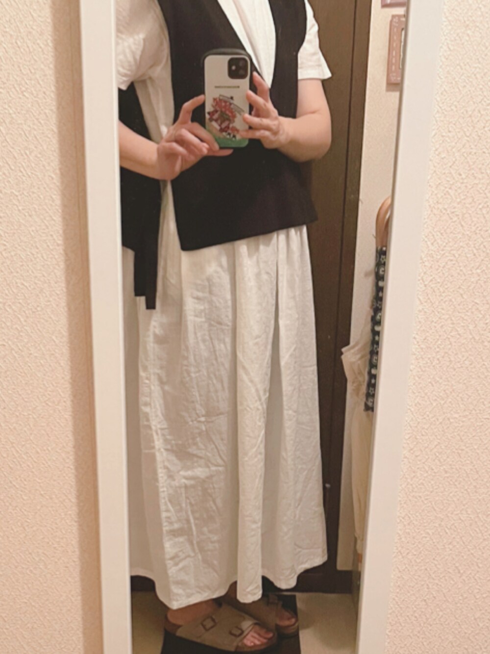 ブラック系のベスト、ホワイト系のワンピース、ベージュ系のサンダルを着用したレディースの夏コーディネートの3枚目の写真