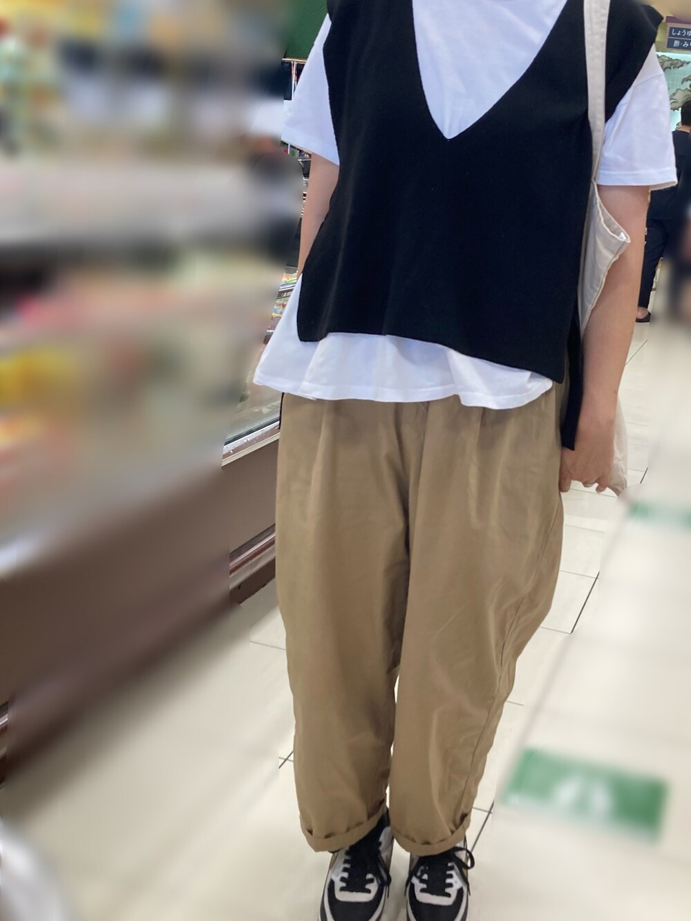 ブラック系のベスト、ベージュ系のその他パンツ、ブラック系のスニーカーを着用したレディースの秋コーディネートの2枚目の写真