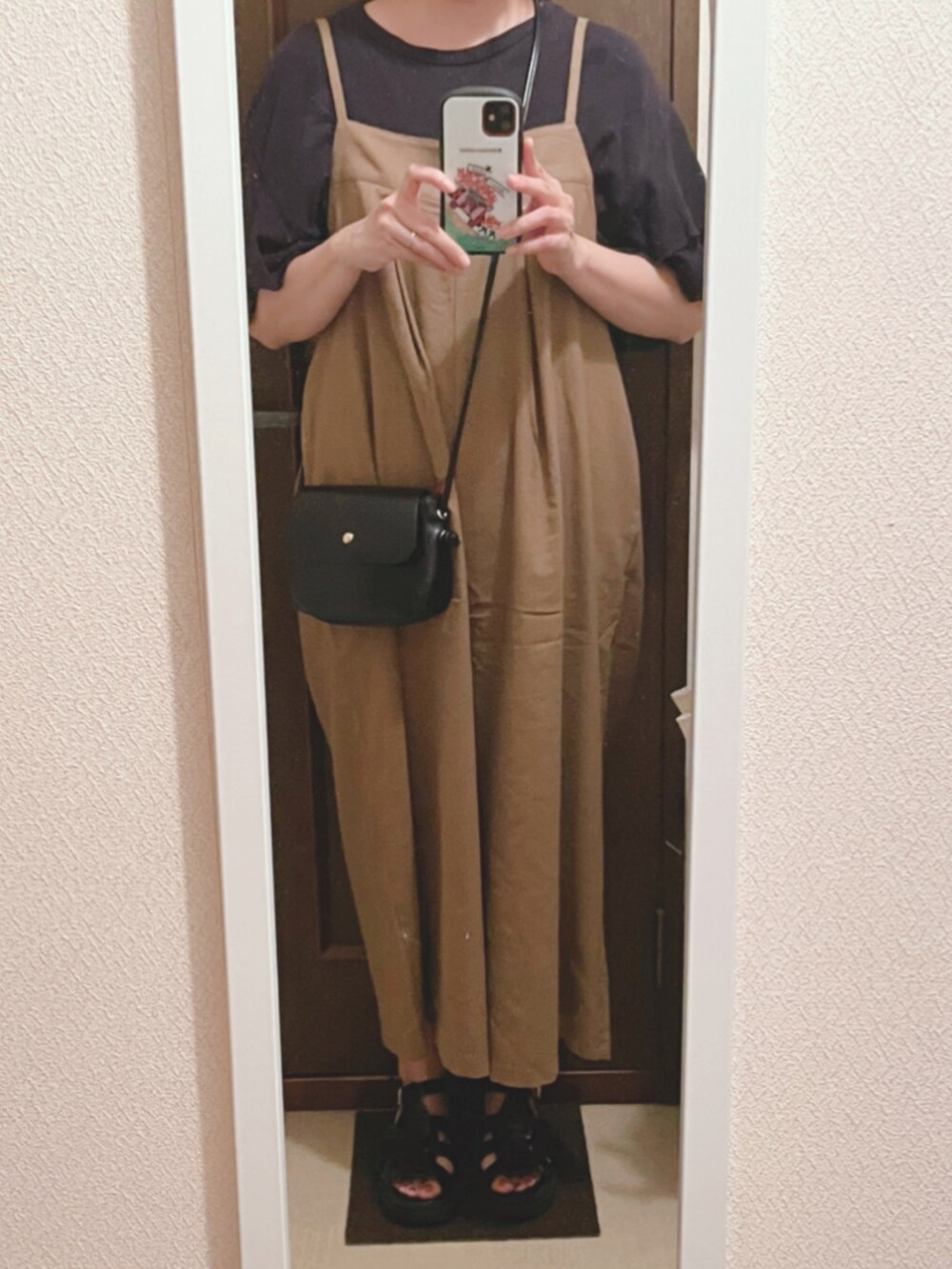 ブラック系のTシャツ/カットソー、ベージュ系のサロペット/オーバーオール、ブラック系のサンダルを着用したレディースの夏コーディネートの2枚目の写真