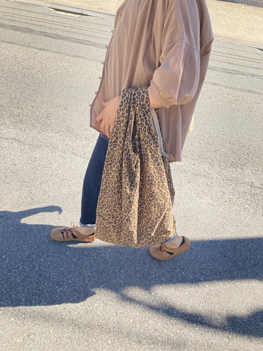 ベージュ系のシャツ/ブラウス、ベージュ系のトートバッグ、ブルー系のデニムパンツを着用したレディースの秋コーディネートの2枚目の写真