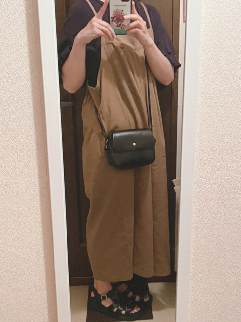 ブラック系のTシャツ/カットソー、ベージュ系のサロペット/オーバーオール、ブラック系のサンダルを着用したレディースの夏コーディネートの3枚目の写真