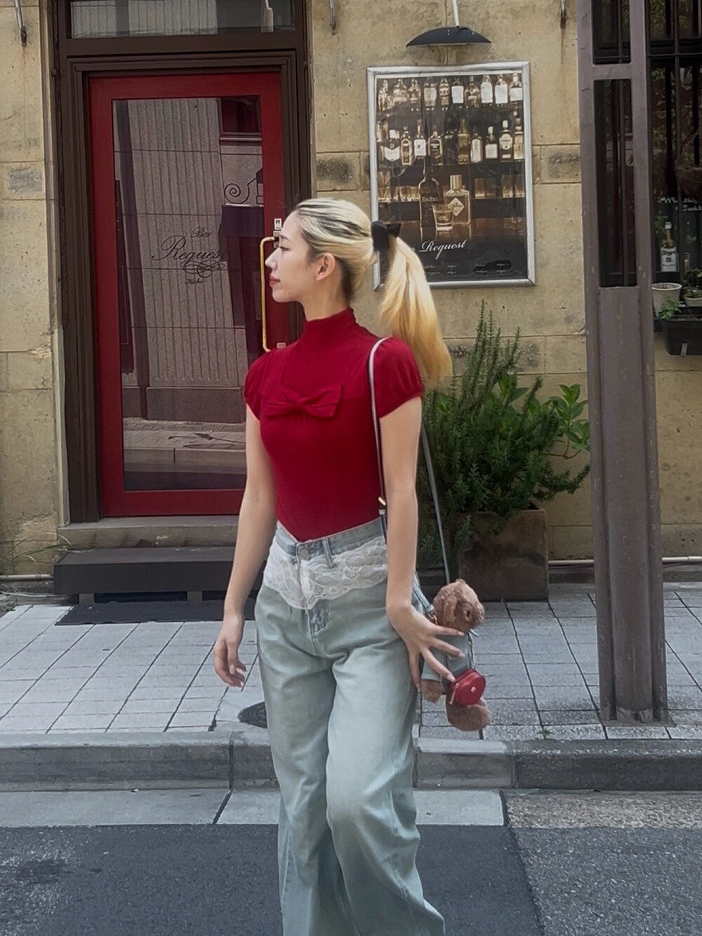 ブルー系のデニムパンツ、レッド系のトップス、ブラウン系のショルダーバッグを着用したレディースの春コーディネートの2枚目の写真