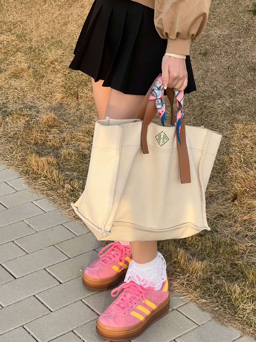 ピンク系のスニーカー、ホワイト系のバッグ、ブラック系のスカートを着用したレディースの春コーディネートの3枚目の写真
