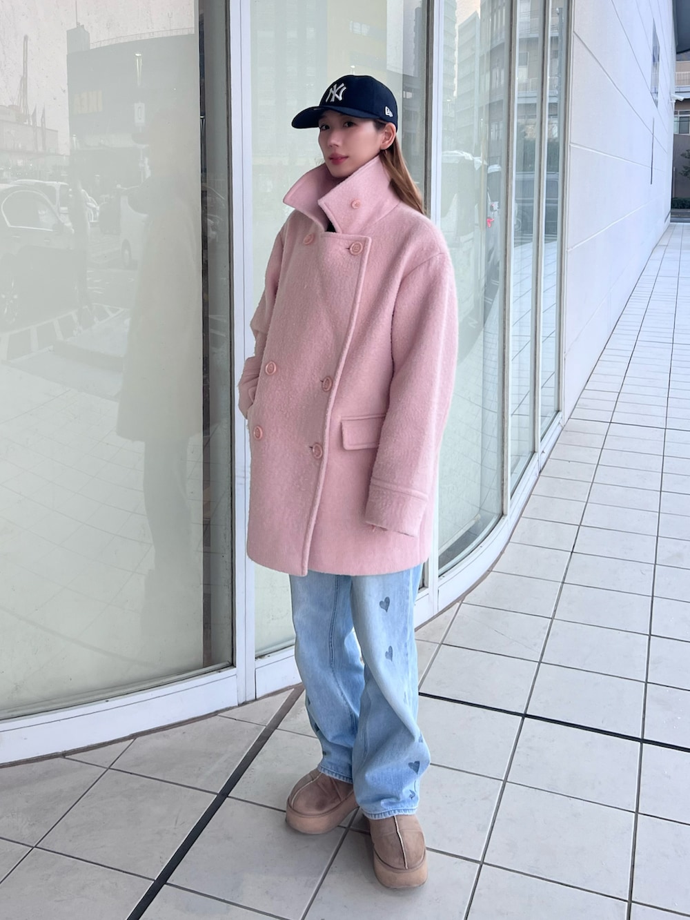 ベージュ系のブーツ、ピンク系のピーコート、ブルー系のデニムパンツを着用したレディースの冬コーディネートの2枚目の写真