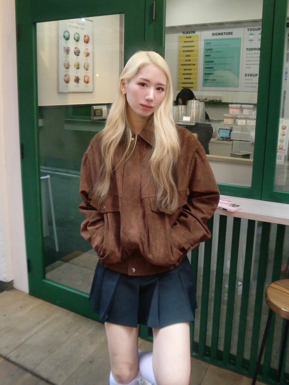 グレー系のスカート、ブラウン系のジャケット/アウター、ホワイト系のスニーカーを着用したレディースの秋コーディネートの2枚目の写真