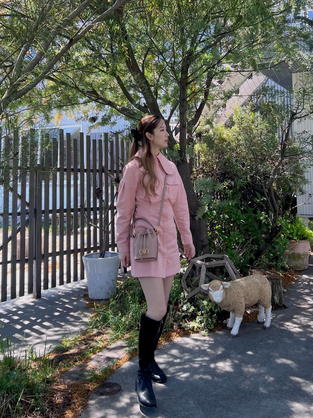 ピンク系のワンピース/ドレス、ピンク系のショルダーバッグ、ブラック系のブーツを着用したレディースの春コーディネートの2枚目の写真