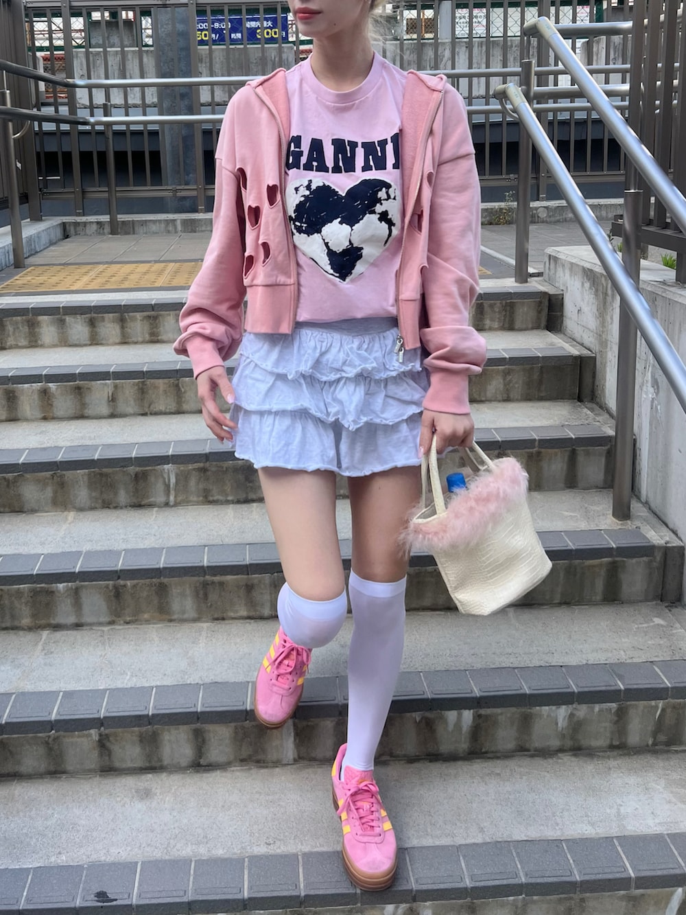 グレー系のスカート、ピンク系のスニーカー、ピンク系のパーカーを着用したレディースの春コーディネートの2枚目の写真