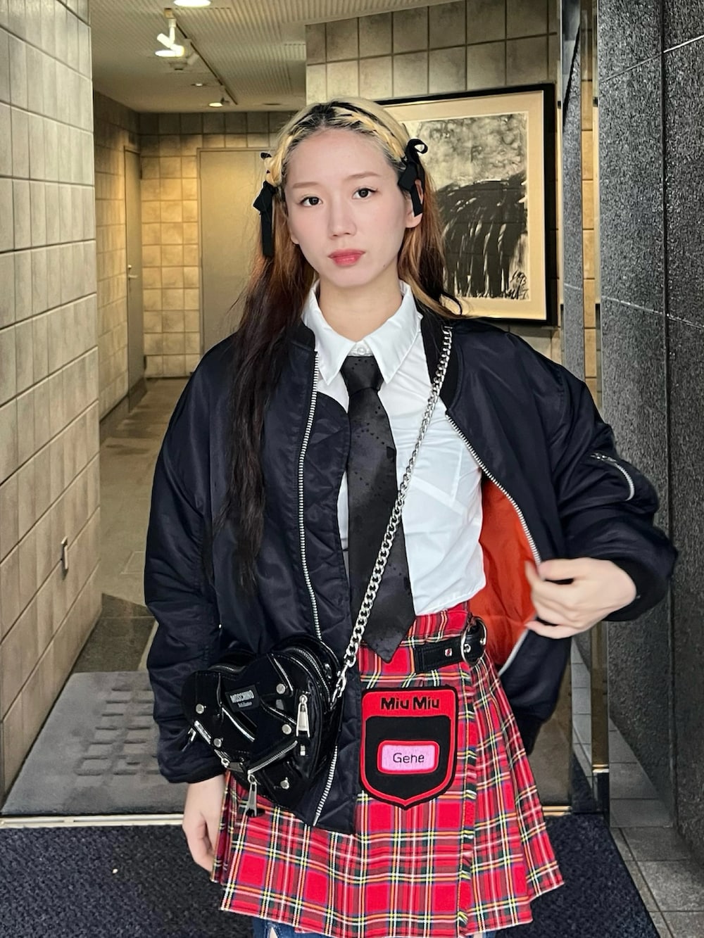 レッド系のスカート、ブルー系のデニムパンツ、ブラック系のブーツを着用したレディースの春コーディネートの2枚目の写真