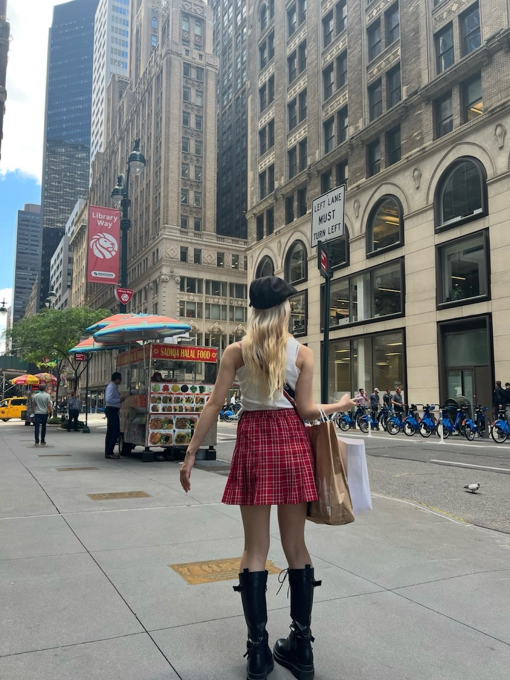 レッド系のスカート、レッド系のショルダーバッグ、ブラック系のブーツを着用したレディースの春コーディネートの2枚目の写真