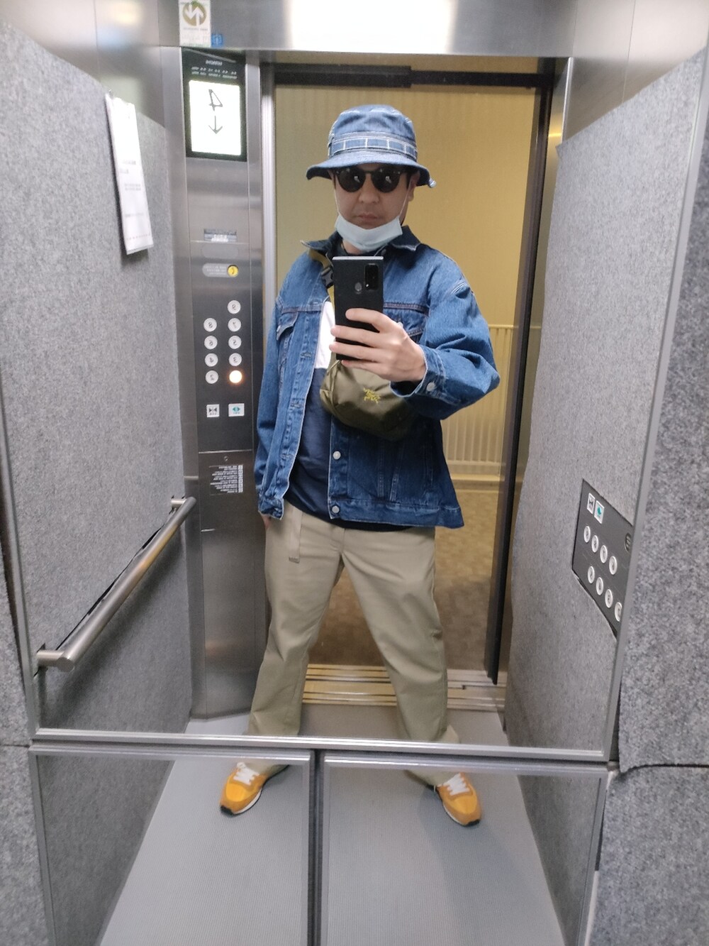 オレンジ系のスニーカー、ベージュ系のパンツ、ブルー系のデニムジャケットを着用したメンズの春コーディネートの2枚目の写真