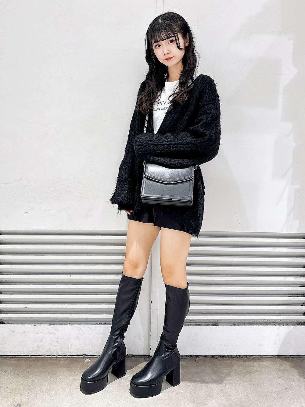 ブラック系のブーツ、ブラック系のカーディガン/ボレロ、ホワイト系のTシャツ/カットソーを着用したレディースの冬コーディネートの2枚目の写真