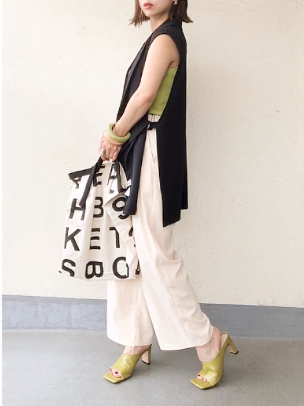 ブルー系のベスト、イエロー系のタンクトップ、ホワイト系のトートバッグを着用したレディースの夏コーディネートの3枚目の写真