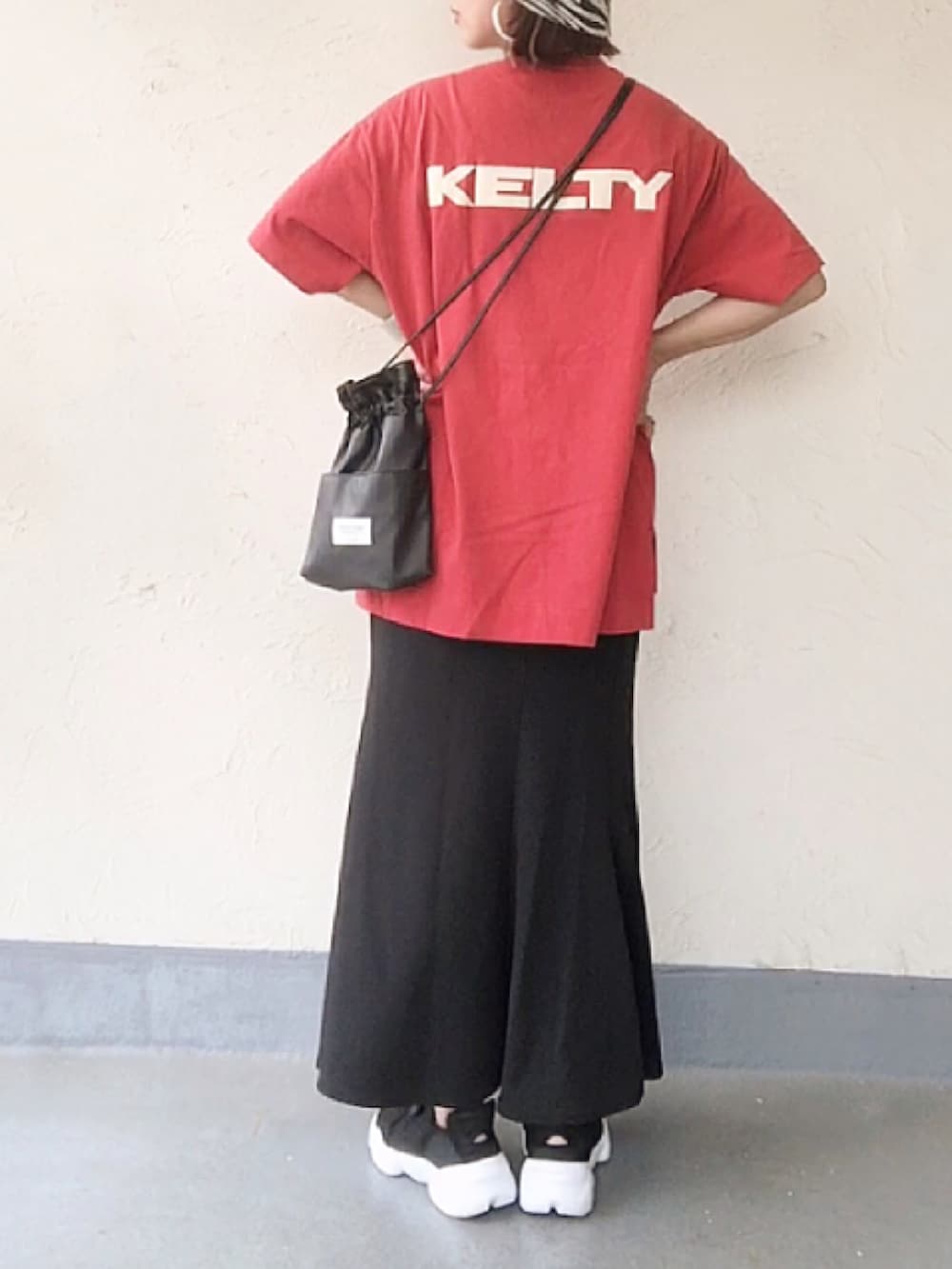 レッド系のTシャツ/カットソー、ブラック系のショルダーバッグ、ブラック系のスカートを着用したレディースの夏コーディネートの2枚目の写真