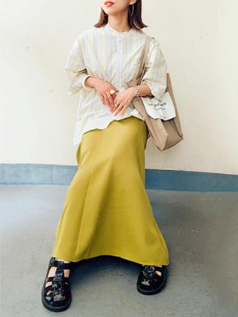 イエロー系のシャツ/ブラウス、ベージュ系のトートバッグ、グリーン系のスカートを着用したレディースの夏コーディネートの2枚目の写真