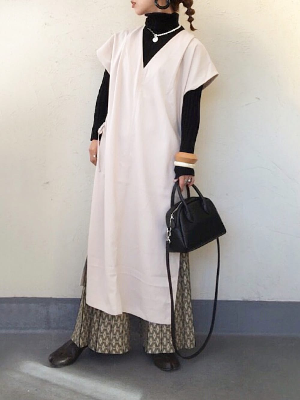 ブラック系のニット/セーター、ベージュ系のワンピース、ブラック系のボストンバッグを着用したレディースの秋コーディネートの2枚目の写真