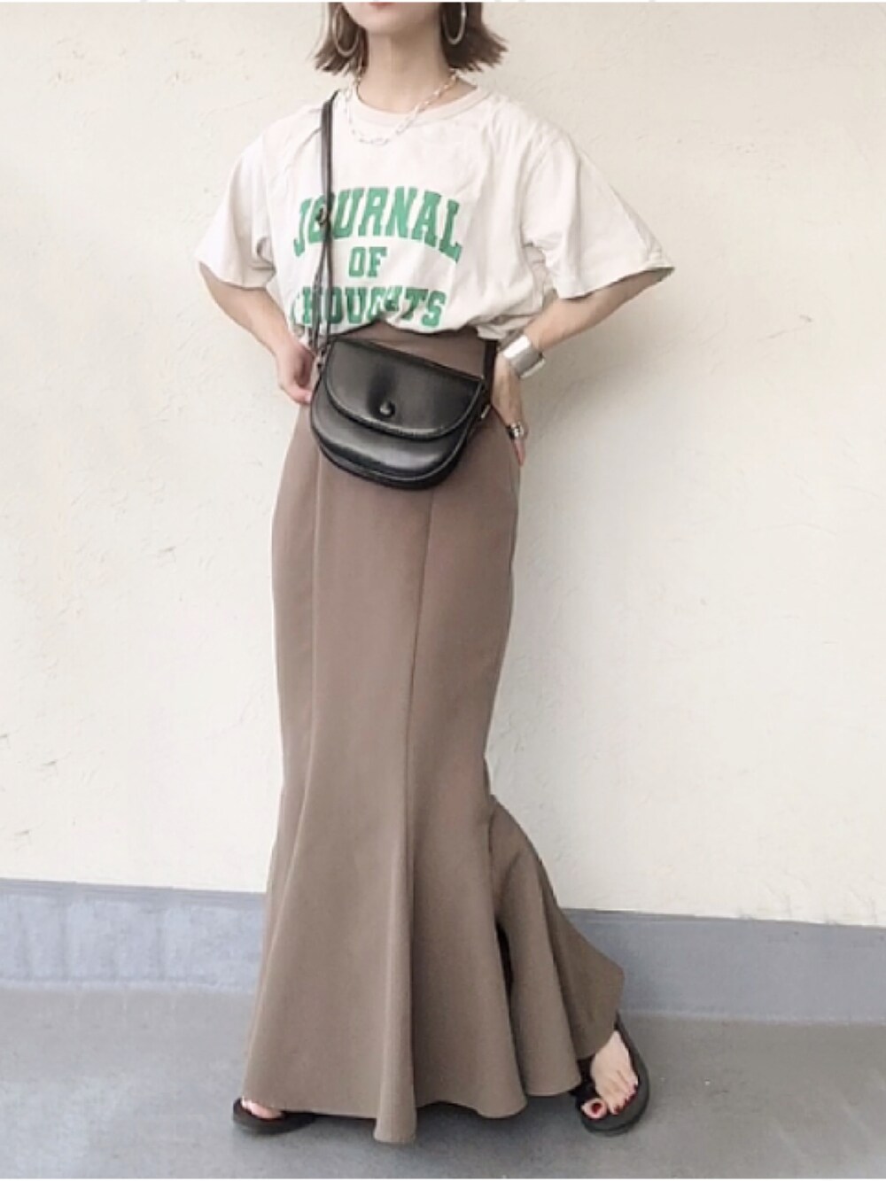 ベージュ系のTシャツ/カットソー、ブラック系のショルダーバッグ、ブラウン系のスカートを着用したレディースの夏コーディネートの2枚目の写真