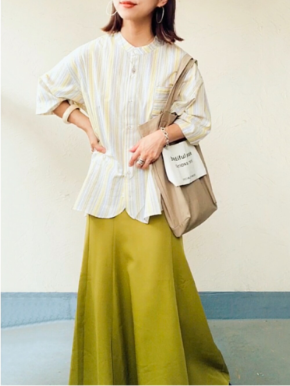 イエロー系のシャツ/ブラウス、ベージュ系のトートバッグ、グリーン系のスカートを着用したレディースの夏コーディネートの3枚目の写真