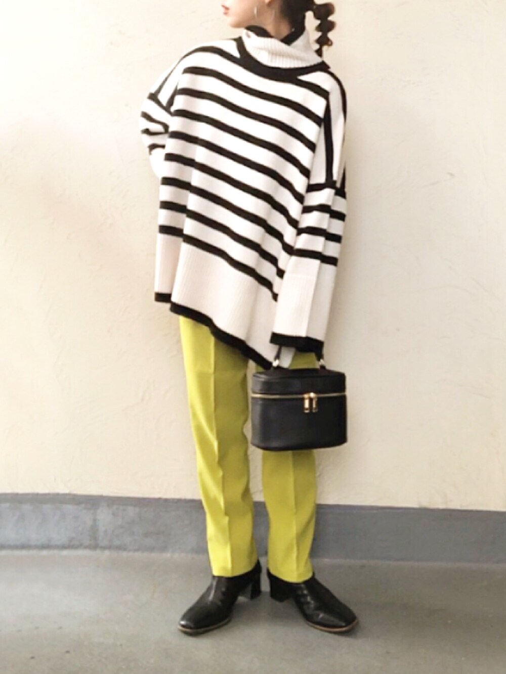 ホワイト系のニット/セーター、ブラック系のハンドバッグ、グリーン系のスラックスを着用したレディースの冬コーディネートの3枚目の写真