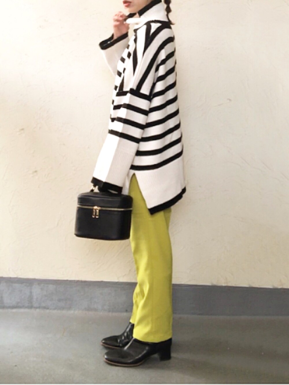 ホワイト系のニット/セーター、ブラック系のハンドバッグ、グリーン系のスラックスを着用したレディースの冬コーディネートの2枚目の写真