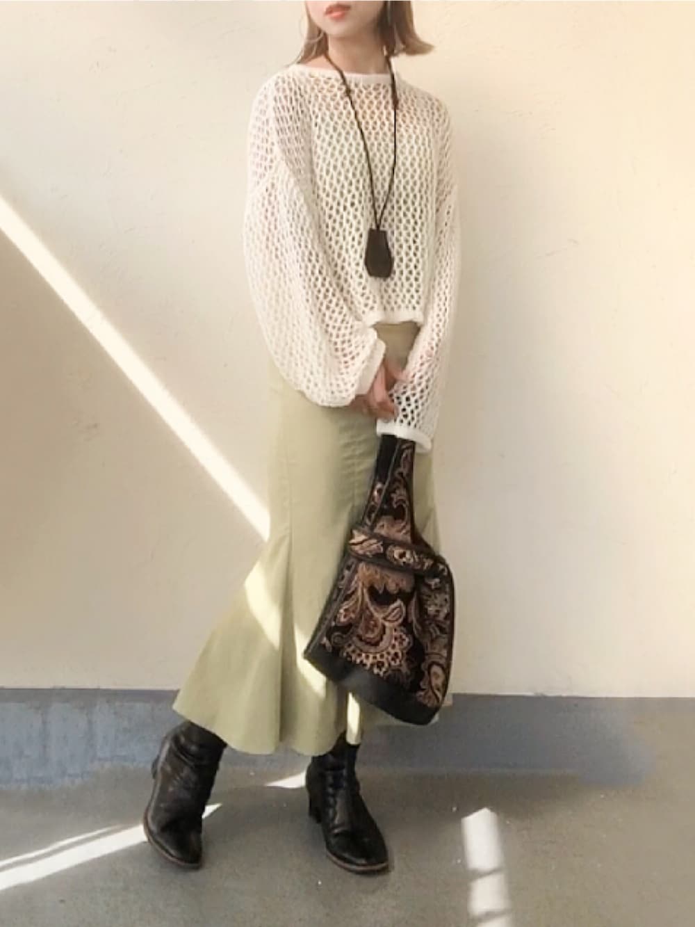 ホワイト系のニット/セーター、グリーン系のワンピース、ブラック系のトートバッグを着用したレディースの秋コーディネートの2枚目の写真