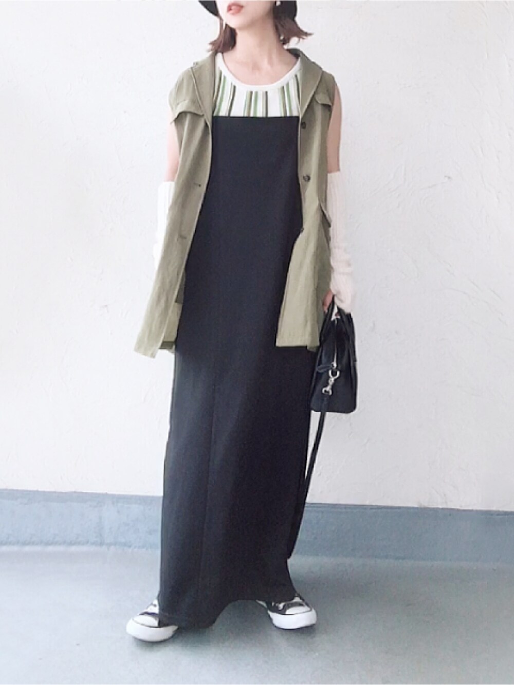 グリーン系のベスト、ブラック系のボストンバッグ、ブラック系のスニーカーを着用したレディースの秋コーディネートの2枚目の写真