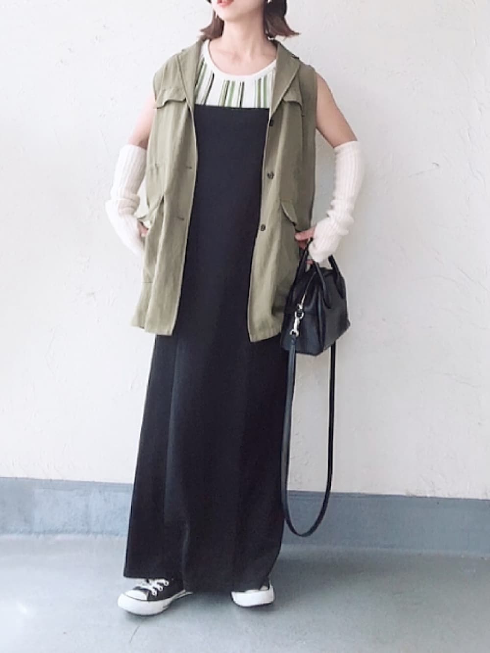 グリーン系のベスト、ブラック系のボストンバッグ、ブラック系のスニーカーを着用したレディースの秋コーディネートの3枚目の写真