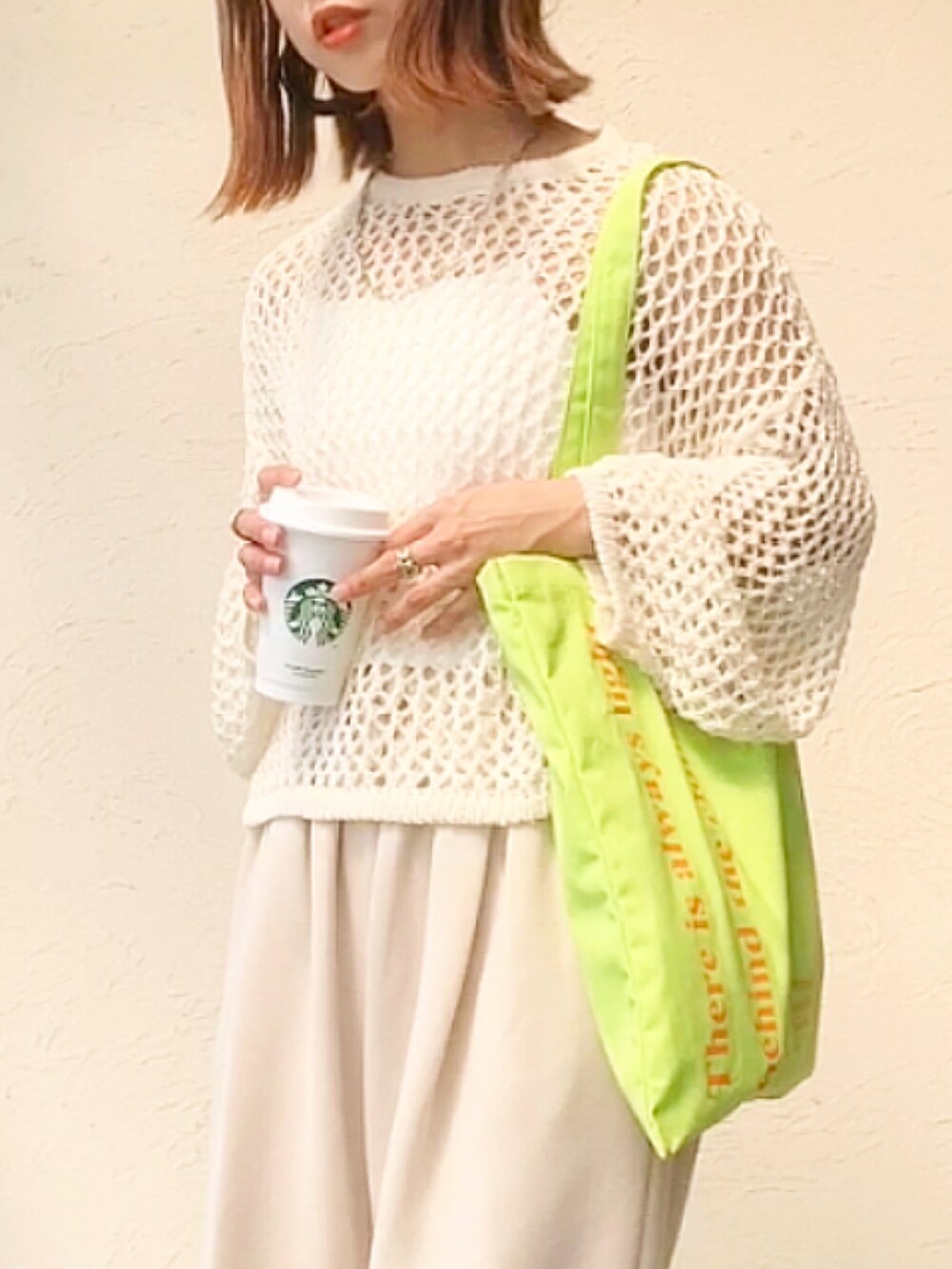 ホワイト系のニット/セーター、グリーン系のトートバッグ、ホワイト系のスウェットパンツを着用したレディースの春コーディネートの3枚目の写真