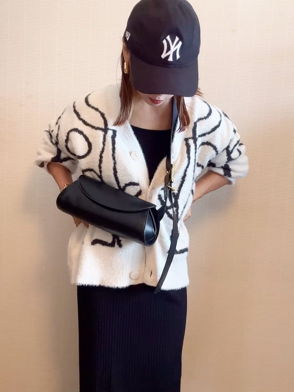 ホワイト系のカーディガン/ボレロ、ブラウン系のショルダーバッグ、ブラック系のスカートを着用したレディースの秋コーディネートの2枚目の写真