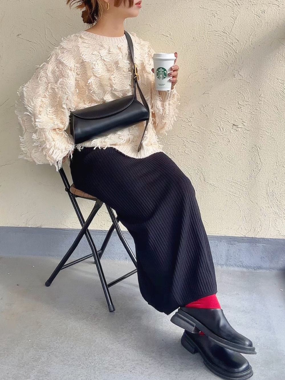 ホワイト系のニット/セーター、ブラウン系のショルダーバッグ、ブラック系のスカートを着用したレディースの秋コーディネートの2枚目の写真
