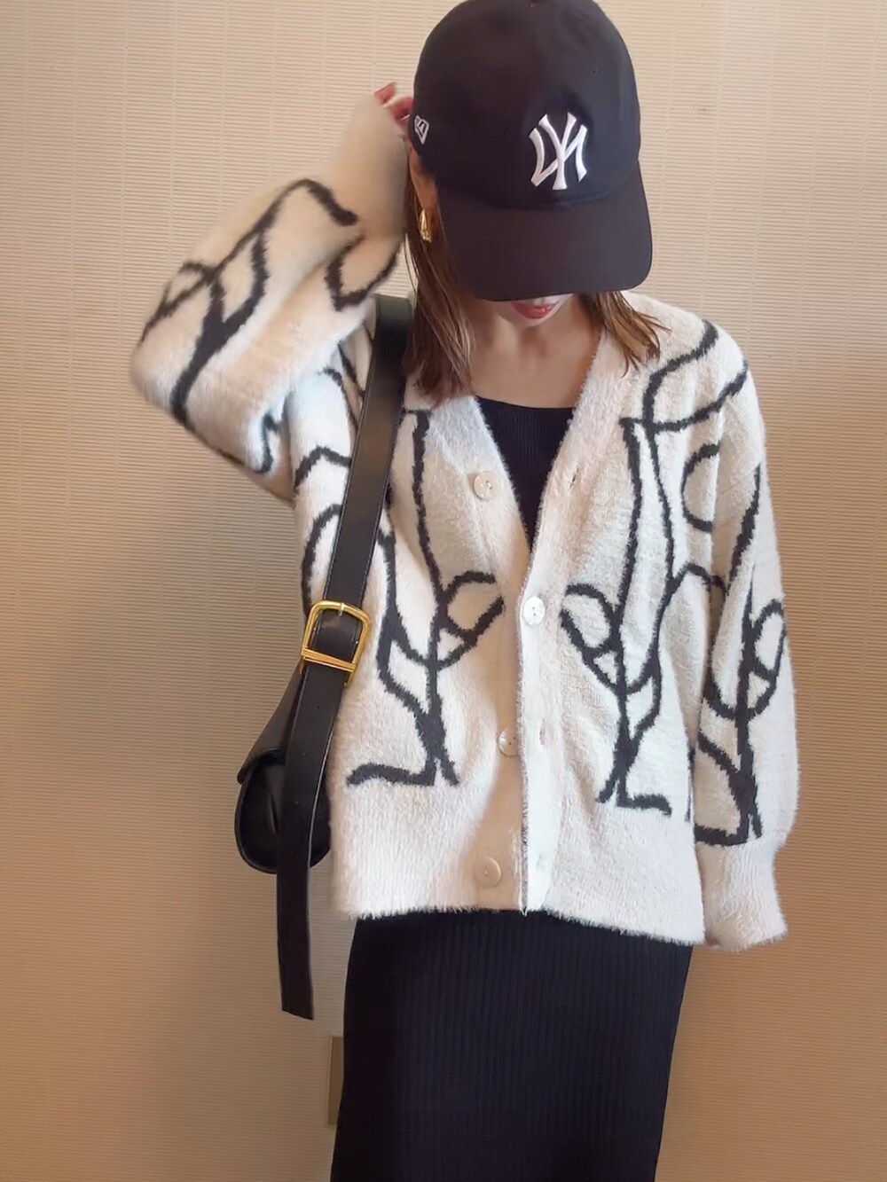 ホワイト系のカーディガン/ボレロ、ブラウン系のショルダーバッグ、ブラック系のスカートを着用したレディースの秋コーディネートの4枚目の写真