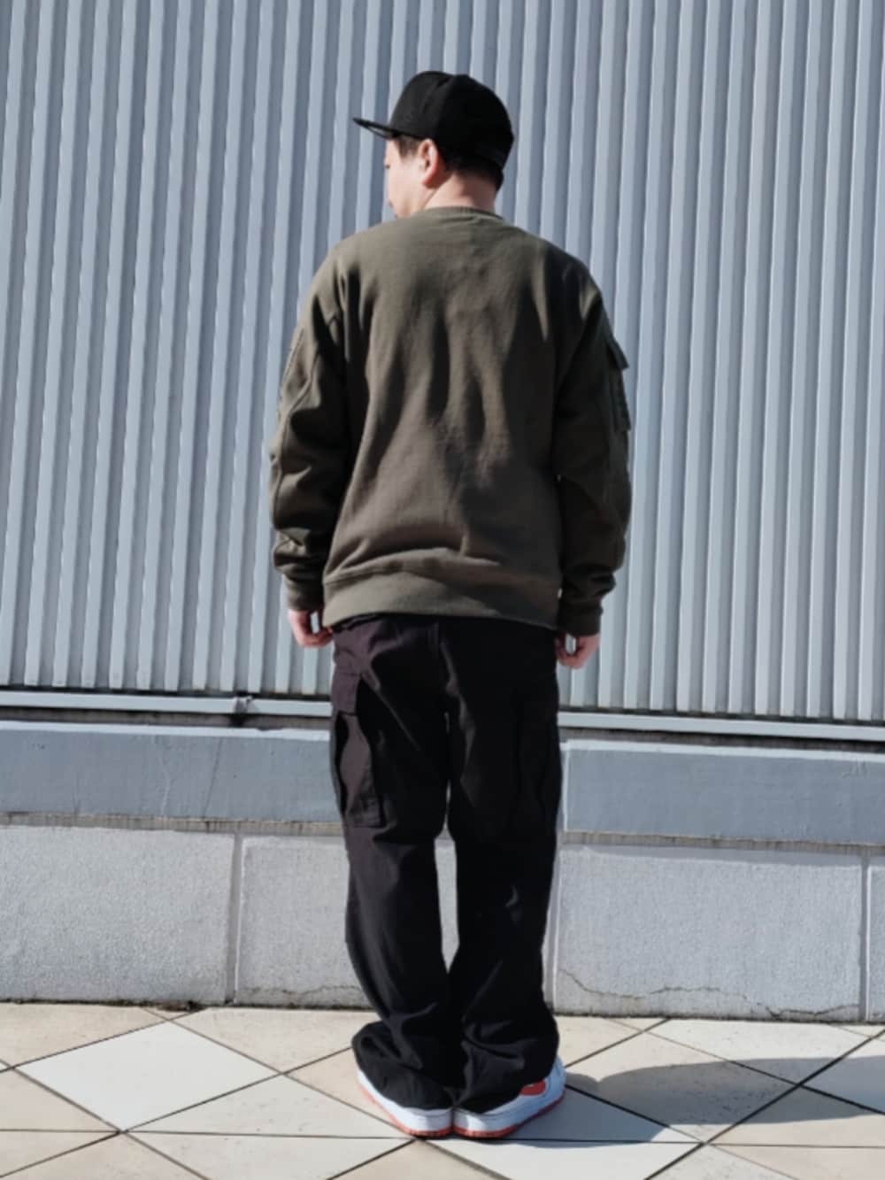 グリーン系のスウェット、ブラック系のカーゴパンツ、ブラック系のキャップを着用したメンズの冬コーディネートの2枚目の写真