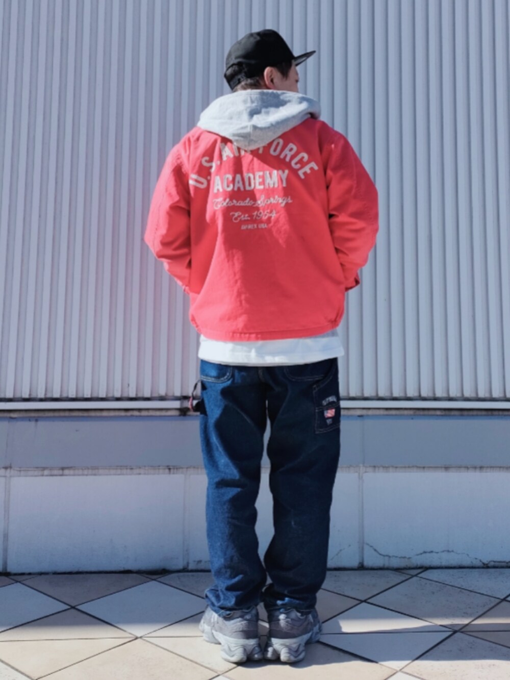 ピンク系のブルゾン、グレー系のパーカー、ブルー系のデニムパンツを着用したメンズの冬コーディネートの2枚目の写真