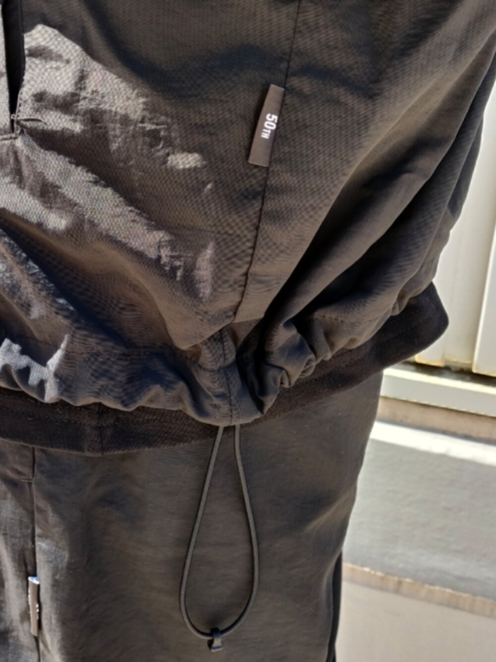 ブラック系のナイロンジャケット、ブラック系のTシャツ/カットソー、ブラック系のその他パンツを着用したメンズの春コーディネートの4枚目の写真