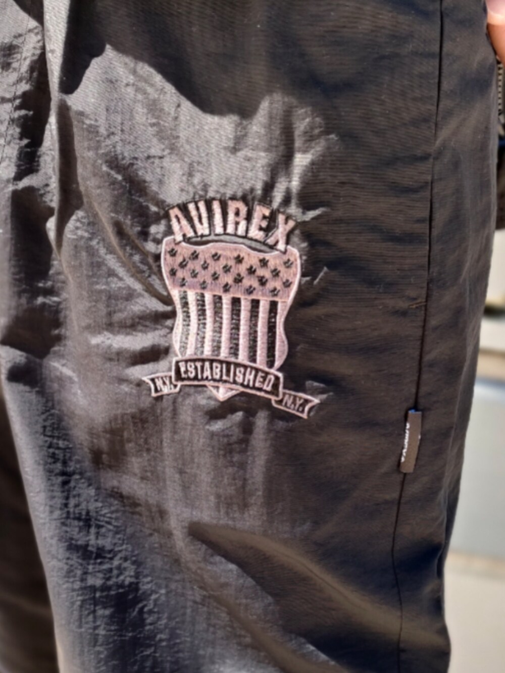 ブラック系のナイロンジャケット、ブラック系のTシャツ/カットソー、ブラック系のその他パンツを着用したメンズの春コーディネートの5枚目の写真