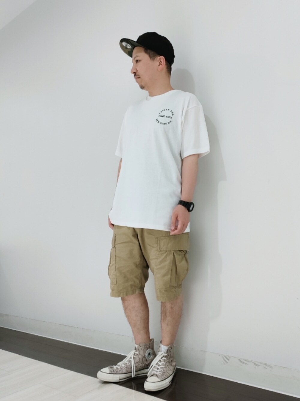 ホワイト系のTシャツ/カットソー、グリーン系のカーゴパンツ、ブラック系のキャップを着用したメンズの夏コーディネートの2枚目の写真