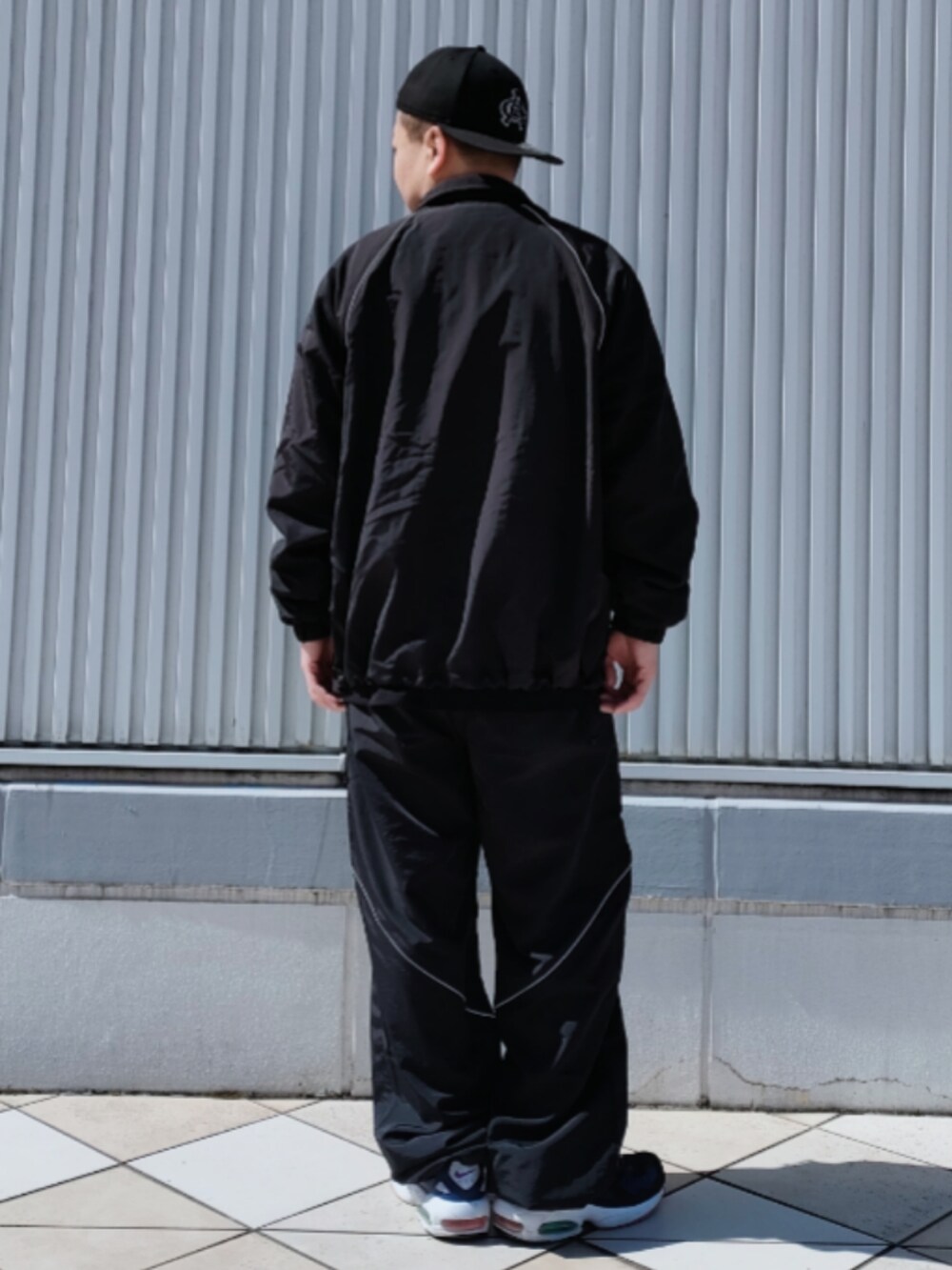 ブラック系のナイロンジャケット、ブラック系のTシャツ/カットソー、ブラック系のその他パンツを着用したメンズの春コーディネートの2枚目の写真