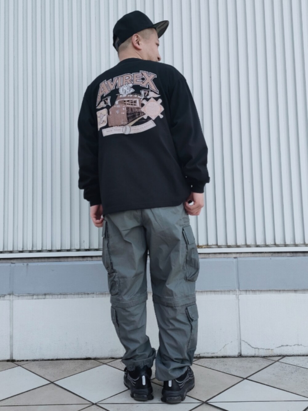 ブラック系のTシャツ/カットソー、グリーン系のカーゴパンツ、ブラック系のキャップを着用したメンズの冬コーディネートの2枚目の写真