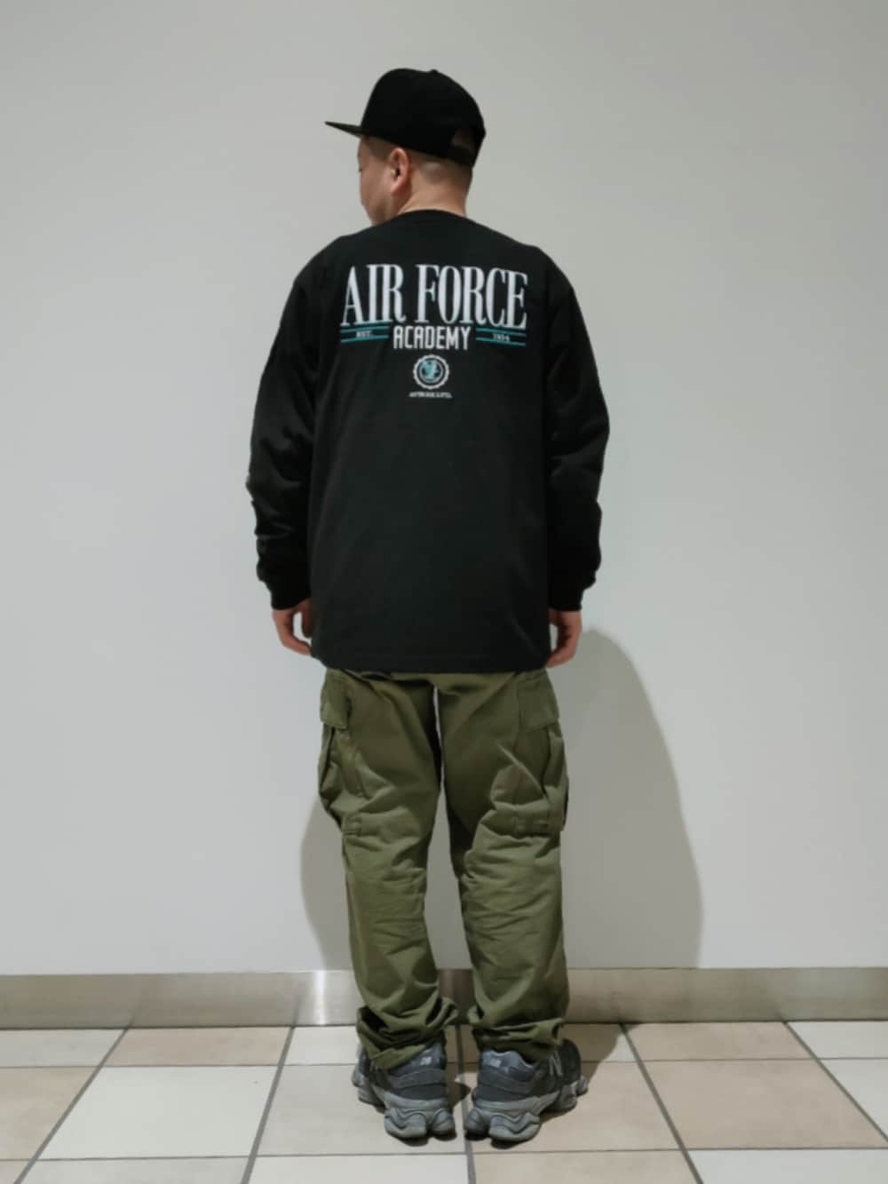 ブラック系のTシャツ/カットソー、グリーン系のカーゴパンツ、ブラック系のキャップを着用したメンズの春コーディネートの2枚目の写真