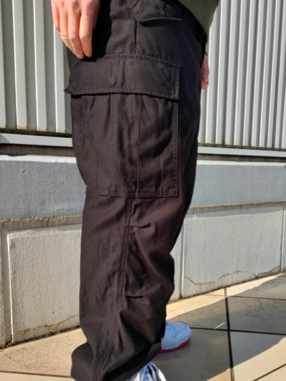グリーン系のスウェット、ブラック系のカーゴパンツ、ブラック系のキャップを着用したメンズの冬コーディネートの5枚目の写真