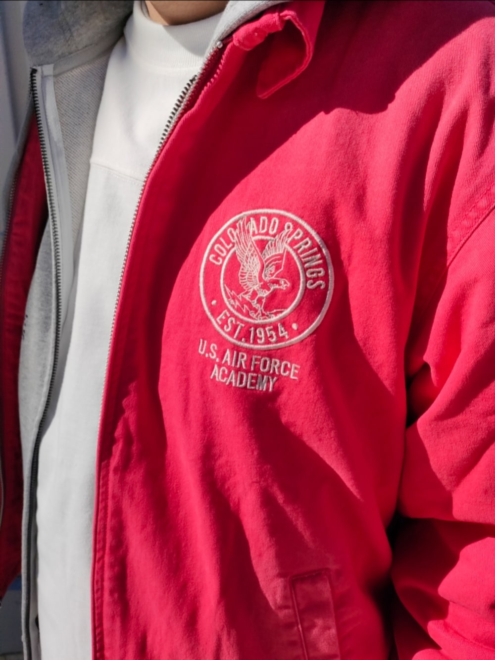 ピンク系のブルゾン、グレー系のパーカー、ブルー系のデニムパンツを着用したメンズの冬コーディネートの3枚目の写真